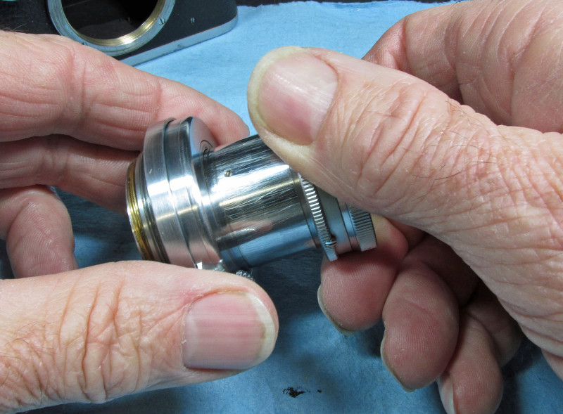 hold the outer knurled ring in one hand and the base in the other (with lens tube fully extended) and turn ccw (counter-clockwise)