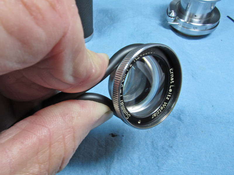 make a loop and wrap it around the rear of the front lens group, behind the front element ring
